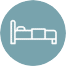 A white icon of a bed with a headboard and pillow is centered on a circular blue-gray background.