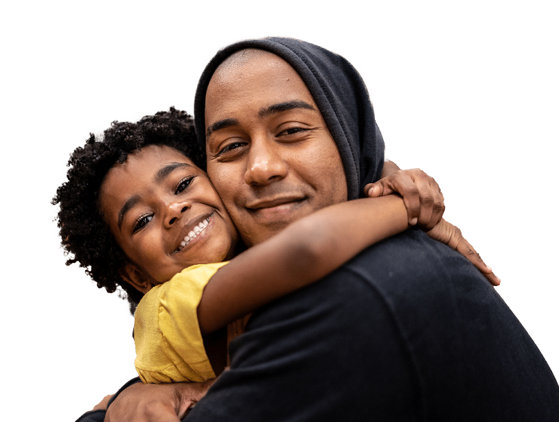 istockphoto-1432208993-1024x1024-1 A smiling child in a yellow shirt hugs an adult wearing a dark hoodie. Both are facing the camera, looking happy and close, against a white background.